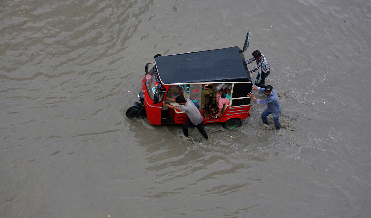 People push a rickshaw through a flooded road after a heavy rainfall in Karachi, Pakistan, on July 7, 2022. (AP)