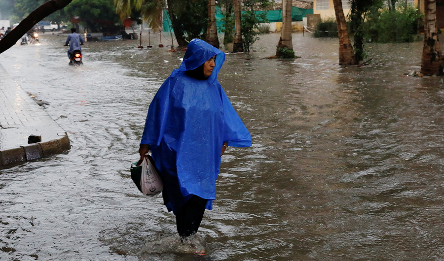 A woman wearing a raincoat wades through a flooded street during the monsoon season in Karachi, Pakistan July 8, 2022. (REUTERS)