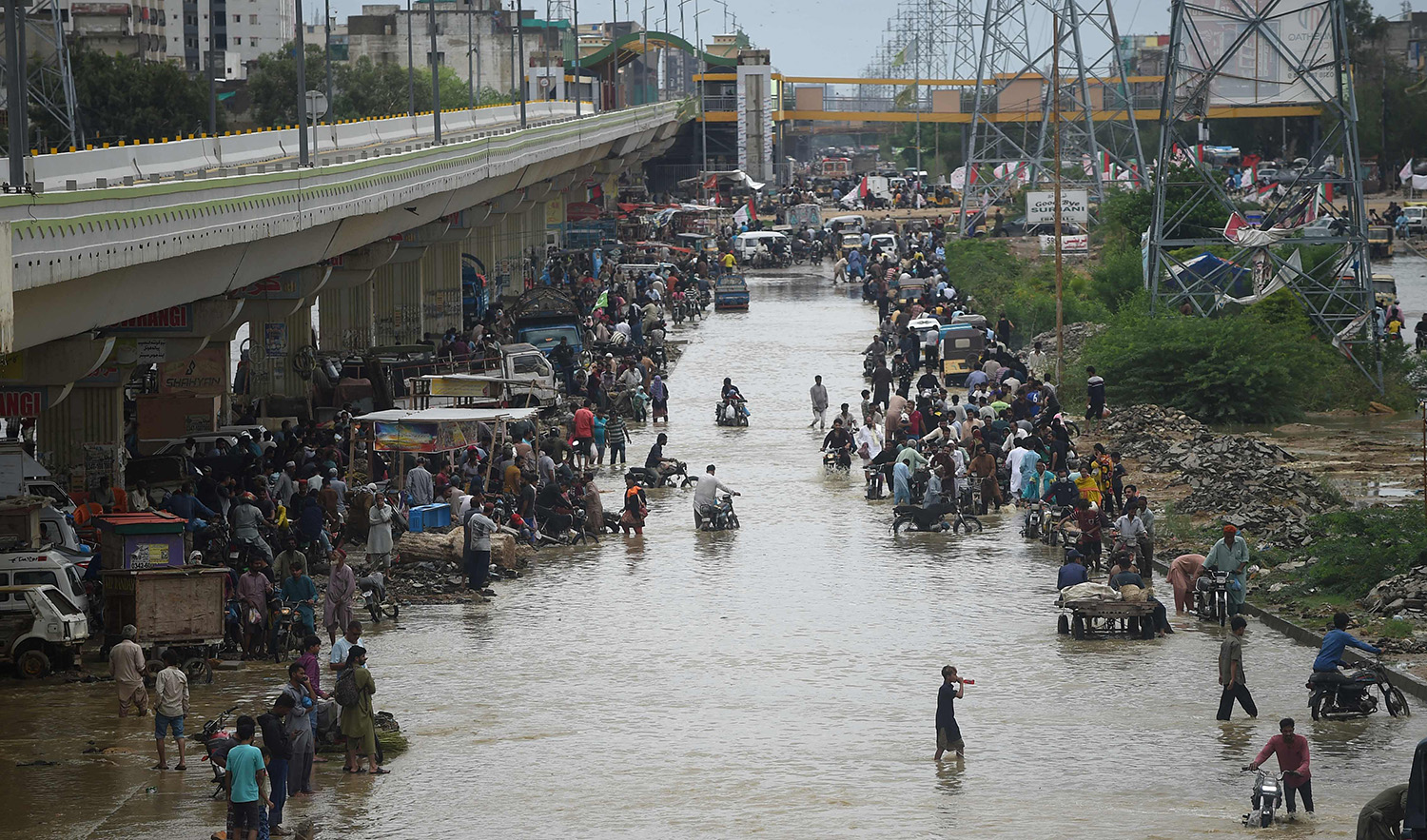 People make their way through a flooded street after a heavy rain shower in Karachi, Pakistan, on July 11, 2022. (AFP)