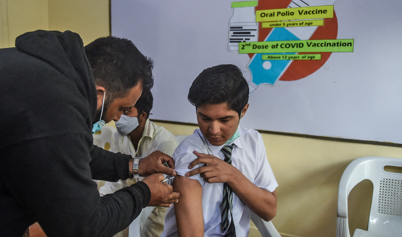 A health worker inoculates a student with a dose of the Pfizer vaccine against the Covid-19 coronavirus at his school in Karachi on January 24, 2022. (AFP/File)