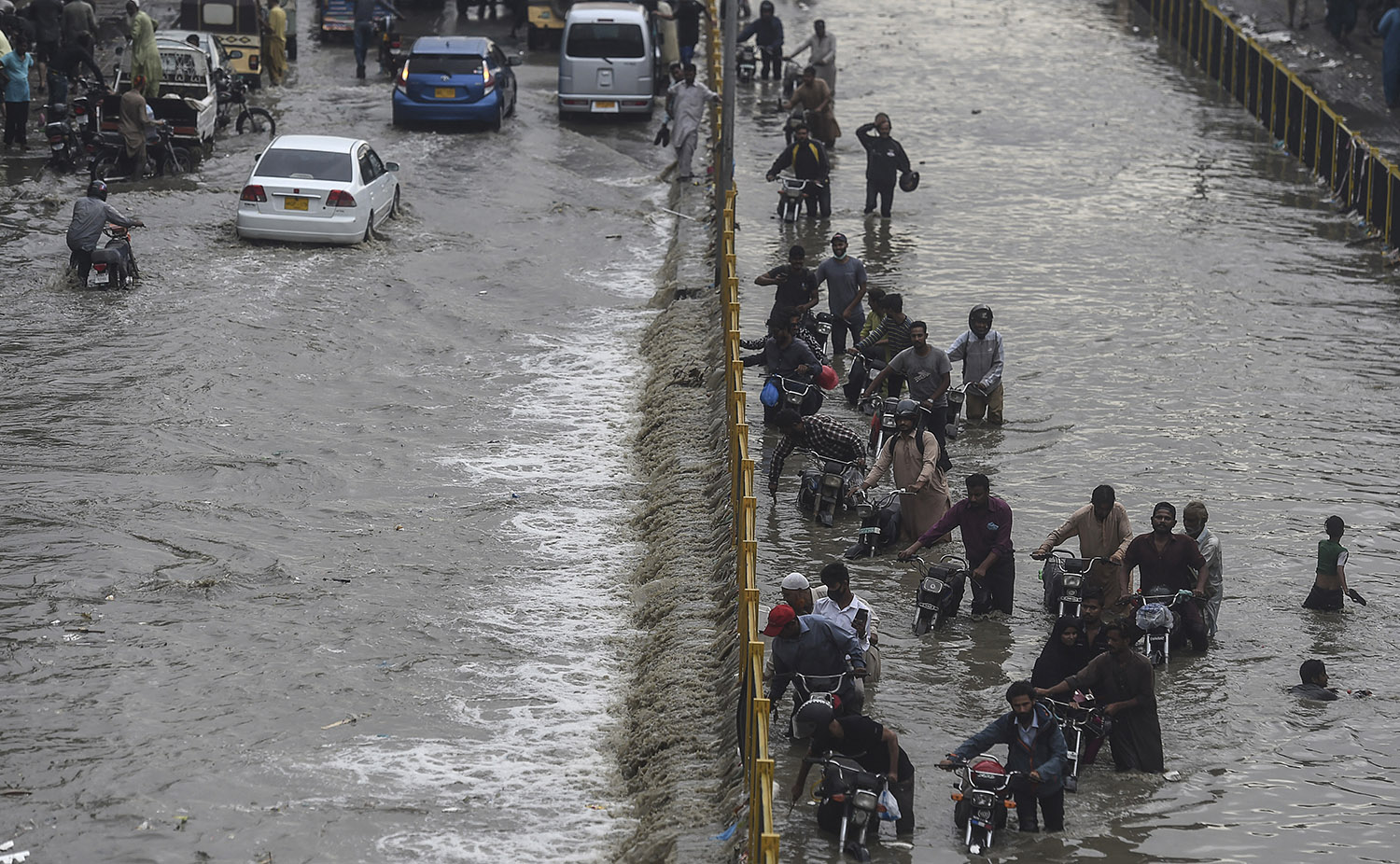 Commuters cross a flooded street after a heavy rainfall in Karachi, Pakistan on September 23, 2021. (AFP/File)