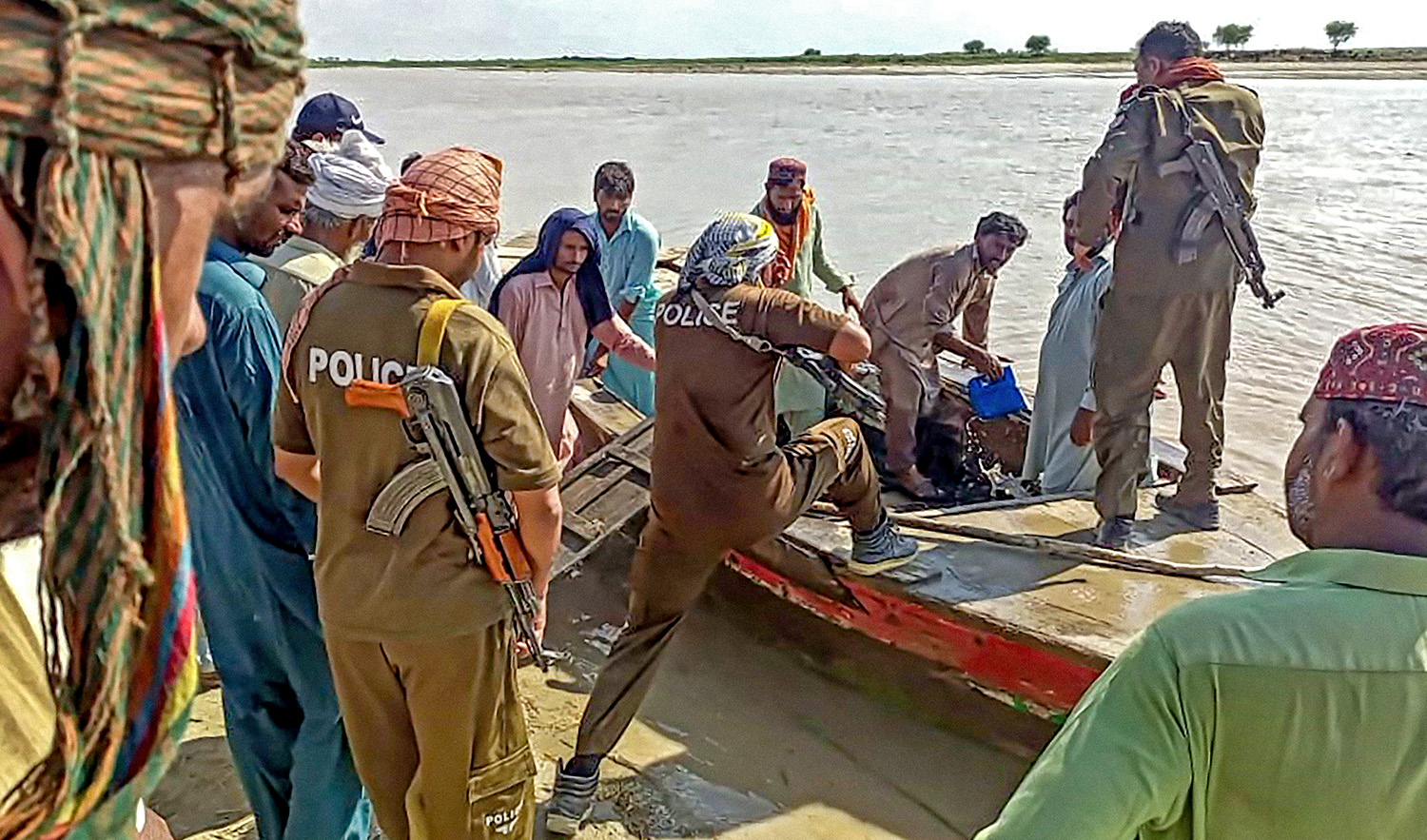 Policemen and local villagers prepare to search for the victims drowned at Indus River after an overcrowded boat carrying a Pakistan wedding party capsized on the outskirt of Sadiqabad town on July 18, 2022. (AFP)