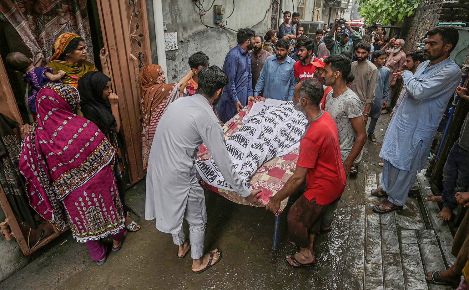People carry the body of a man who died when the roof of his house collapsed due to heavy rains, in Lahore, Pakistan, on July 21, 2022. (AP)