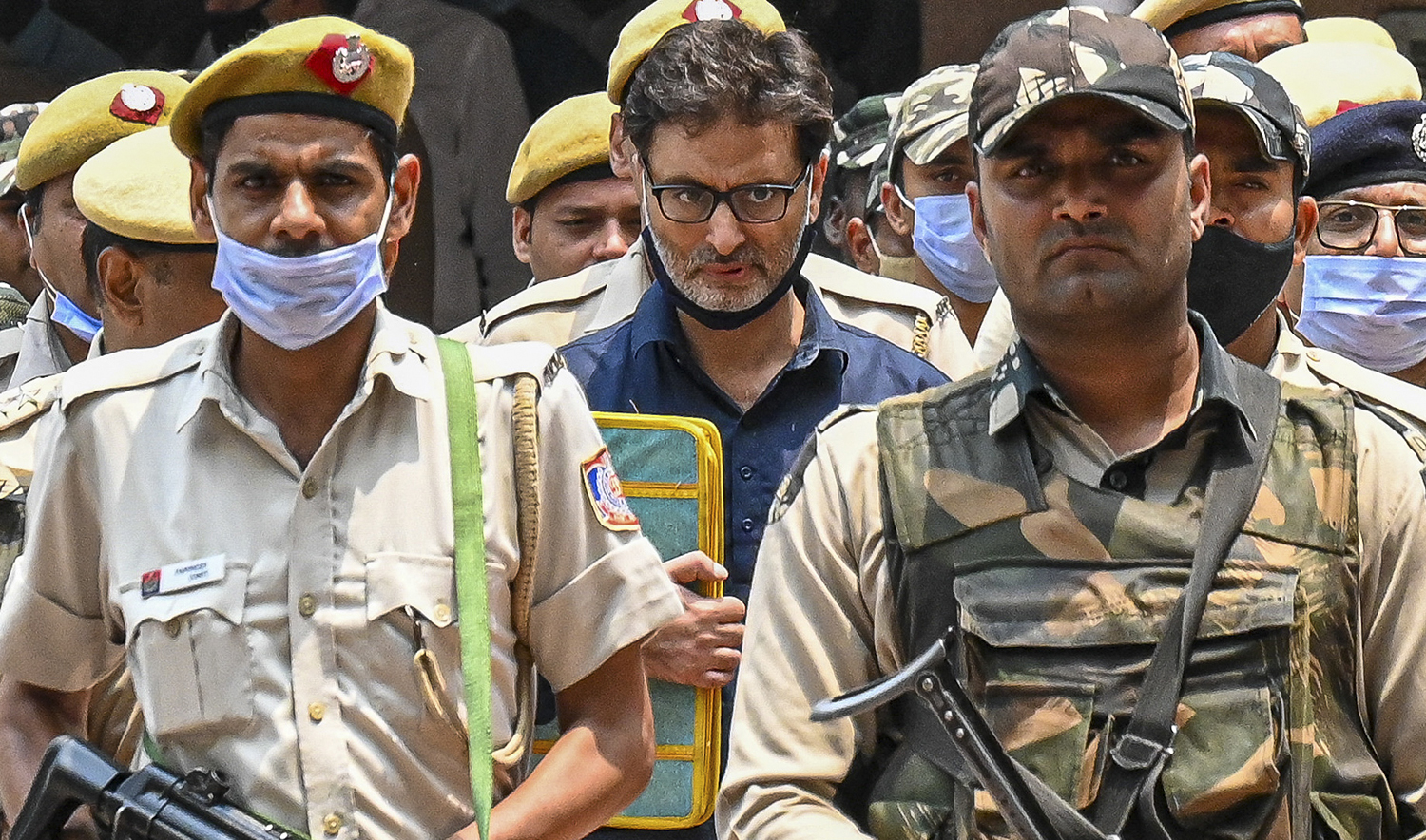 Police and security personnel escort Yasin Malik, center, at Patiala house court in New Delhi on May 25, 2022. (AFP/File)
