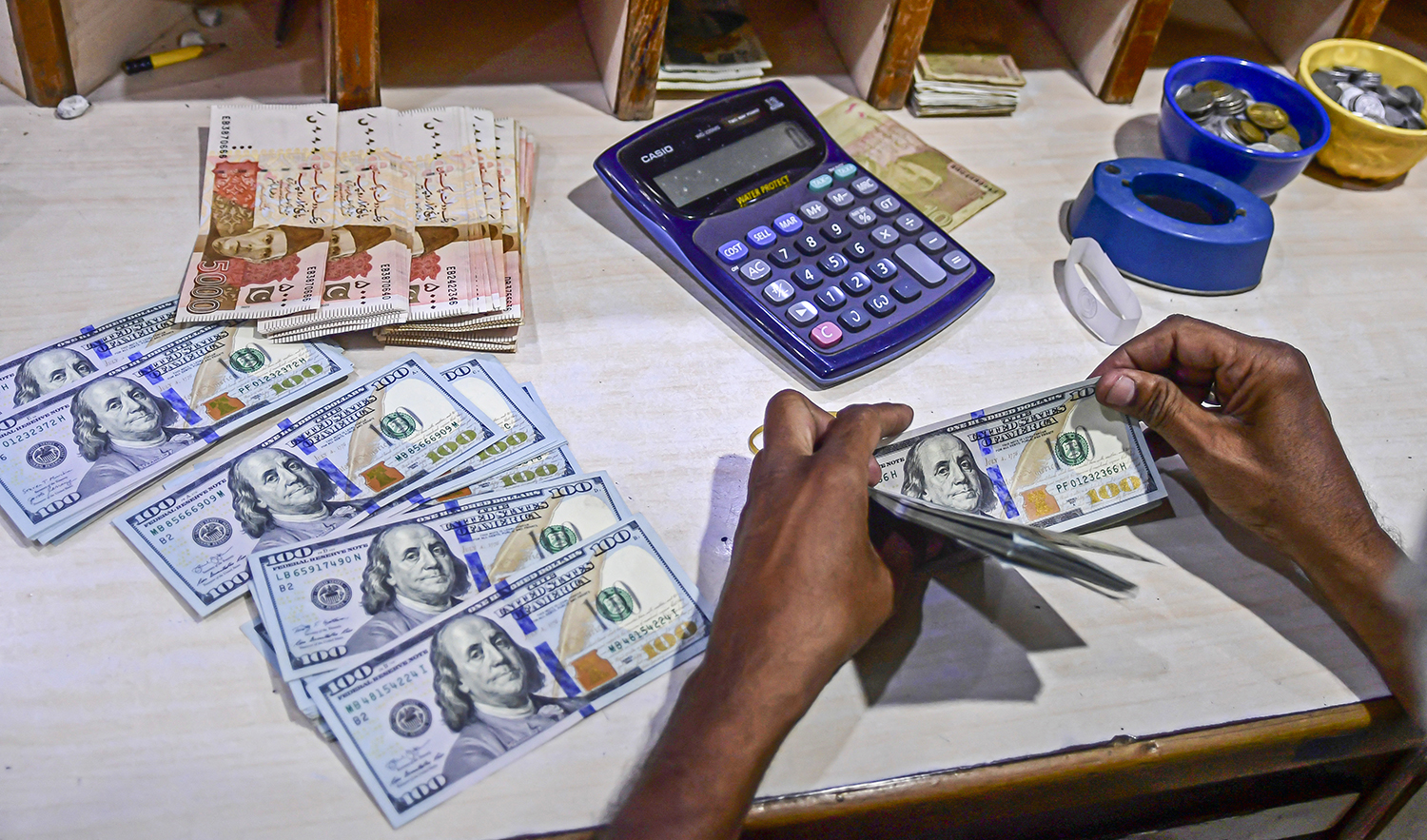 A foreign currency dealer counts US dollar notes at a currency market in Karachi, Pakistan, on July 19, 2022. (AFP)