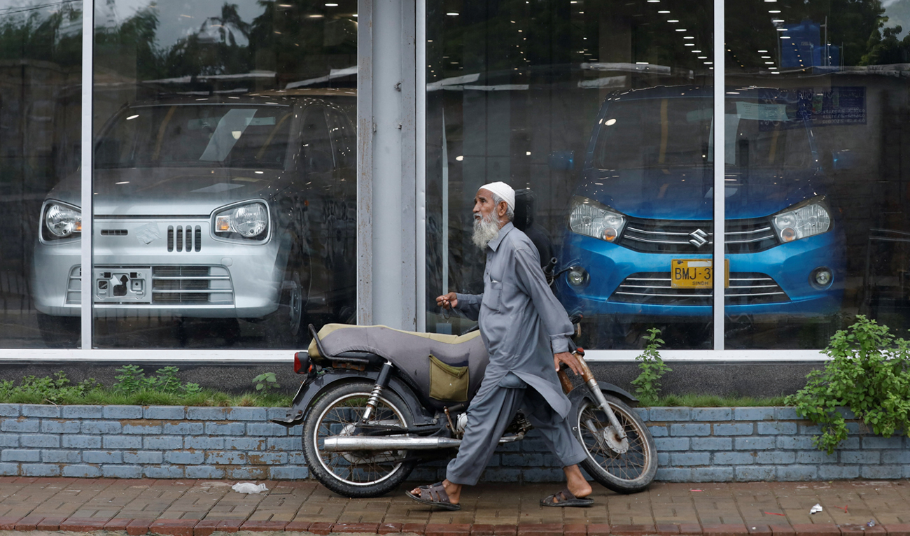 A man walks past a Suzuki outlet, displaying cars in Karachi, Pakistan, July 27, 2022. (REUTERS)