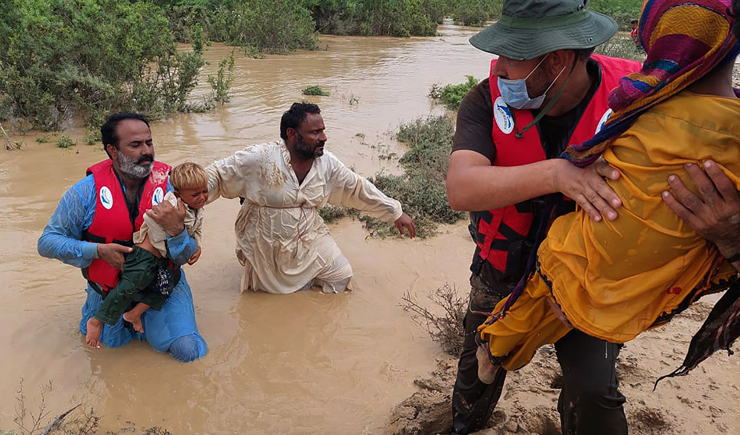 Rescue workers help villagers to evacuate them from flooded area caused by heavy rains, in Lasbella, a district in Pakistan's southwest Balochistan province on July 26, 2022. (AP)