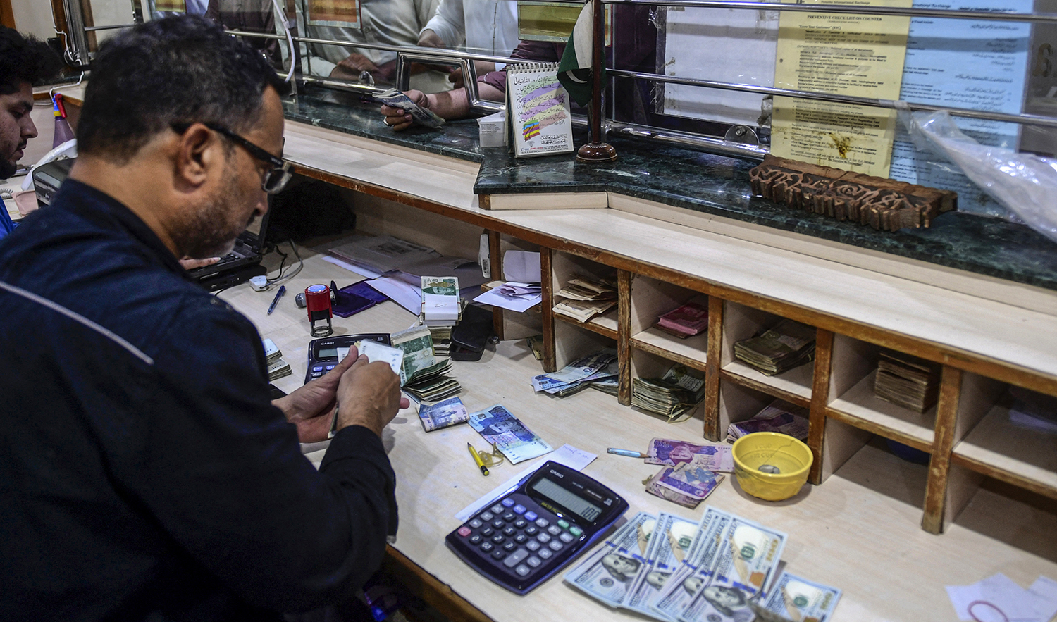 People exchange foreign currency at a shop in Karachi, Pakistan, on April 7, 2022. (AFP/File)