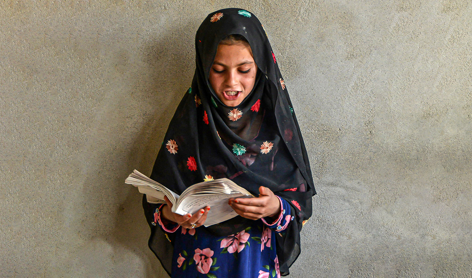 An Afghan girl reads a book inside a private educational center in Panjwai district of Kandahar, Afghanistan, on June 7, 2022. (AFP/File)