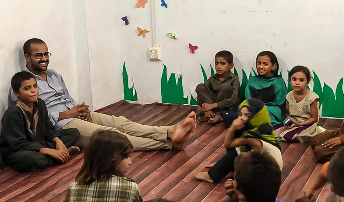 This photo shows young Pakistani educationist Moazzam Shah Bukhari sits with kids of "The Walkway School". (@walkwayschool/Twitter)