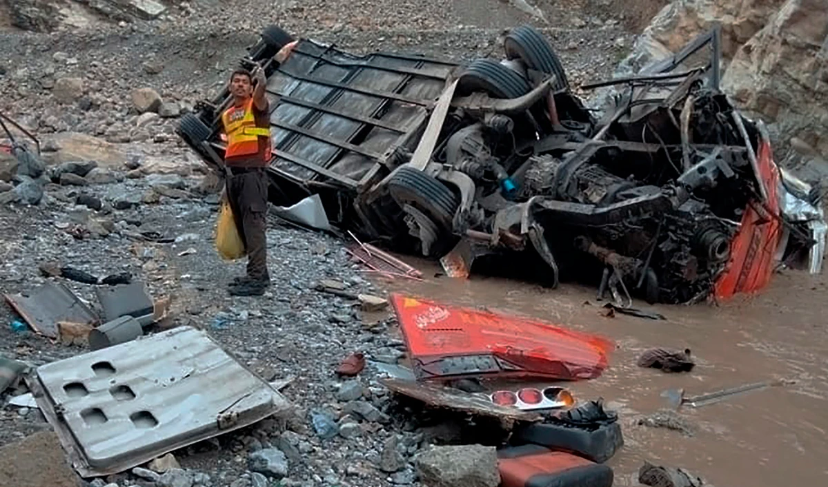 In this photo provided by Baluchistan's rescue department, a rescue worker stands next to the wreck of a passenger bus, in Zhob, Baluchistan province, in southwest Pakistan, Sunday, July 3, 2022. (Baluchistan Rescue Department via AP)