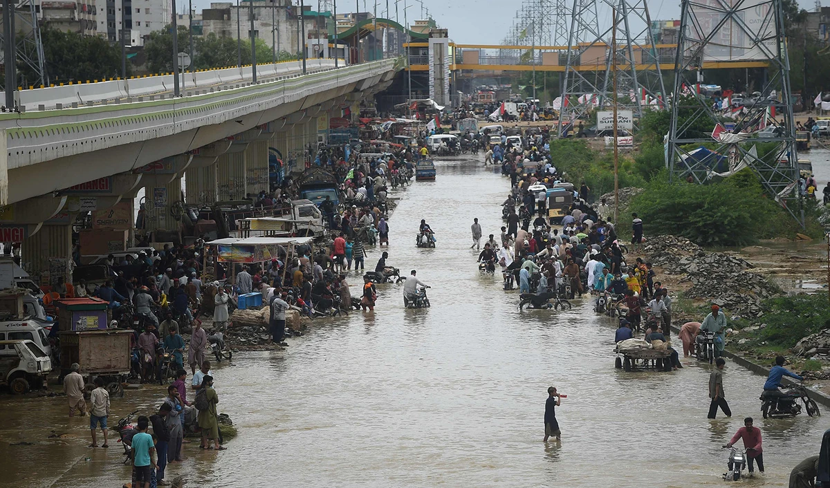 People make their way through a flooded street after a heavy rain shower in Karachi, Pakistan, on July 11, 2022. (AFP)