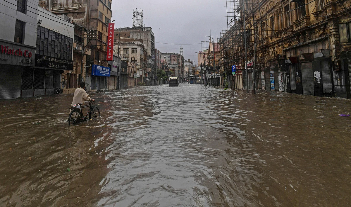A commuter makes his way through a flooded street after a heavy rain shower in Karachi, Pakistan on July 11, 2022. (AFP)