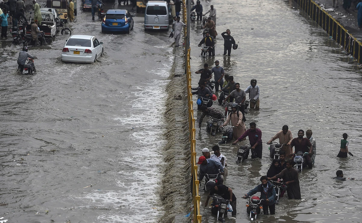 Commuters cross a flooded street after a heavy rainfall in Karachi, Pakistan on September 23, 2021. (AFP/File)