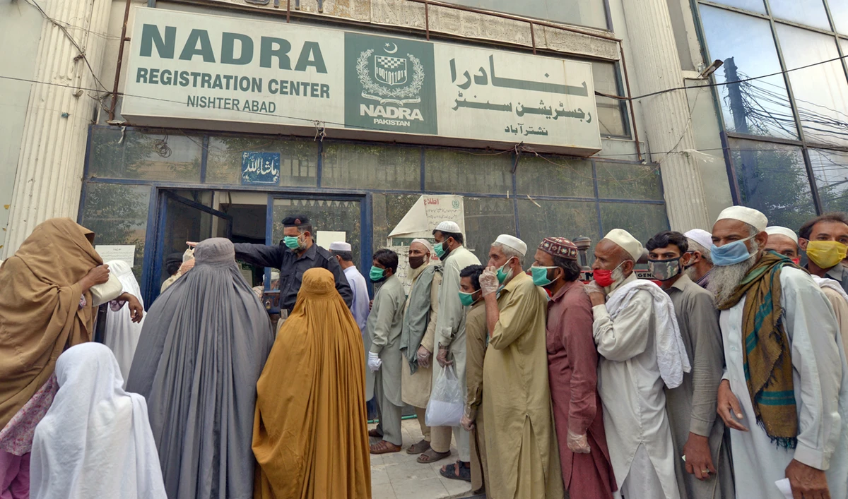 Residents wearing facemasks line up in a queue outside the National Database and Registration Authority (NADRA) office for new registrations and biometric verification in Peshawar, Pakistan on May 4, 2020. (AFP/File)
