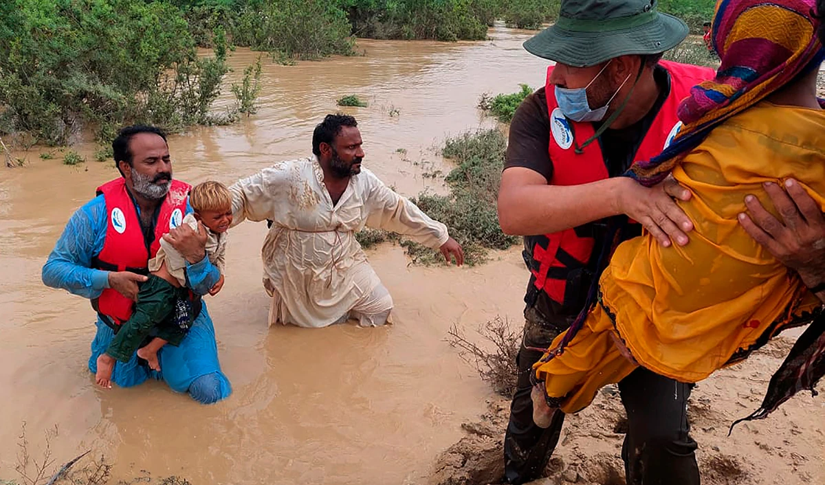 Rescue workers help villagers to evacuate them from flooded area caused by heavy rains, in Lasbella, a district in Pakistan's southwest Balochistan province on July 26, 2022. (AP)