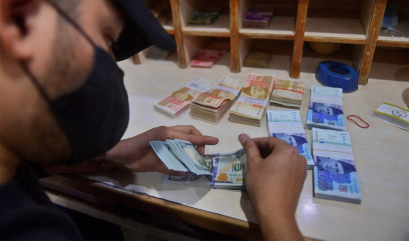 In this picture taken on January 11, 2022, a foreign currency dealer counts US dollar notes at a shop in Karachi, Pakistan, (AFP/File)