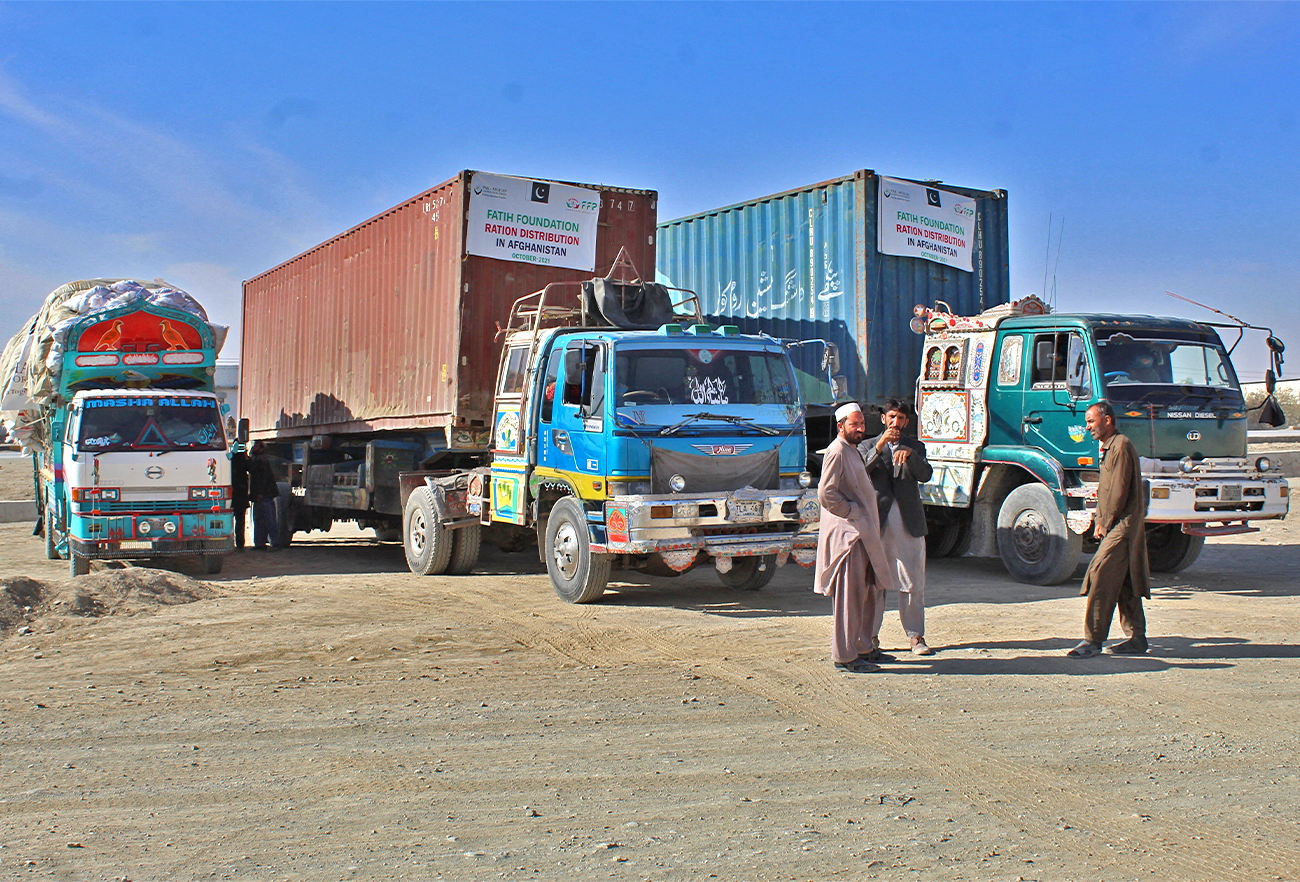 Drivers stand in front of their trucks loaded with relief materials for the distressed Afghan people before crossing through the Chaman border on December 17, 2021. (AFP/File)
