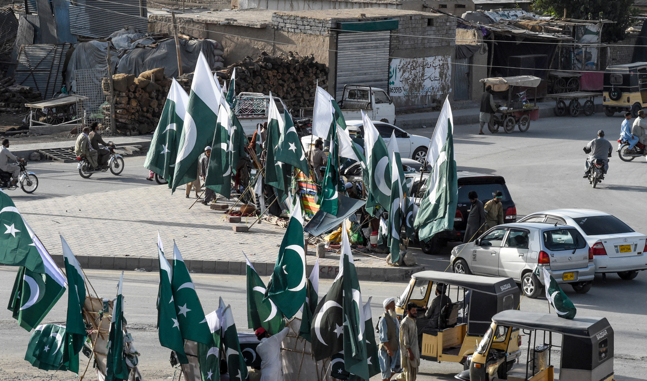 Motorists ride past Pakistani flags displayed on a stall for selling along a street in Quetta on August 13, 2020. (AFP/File)