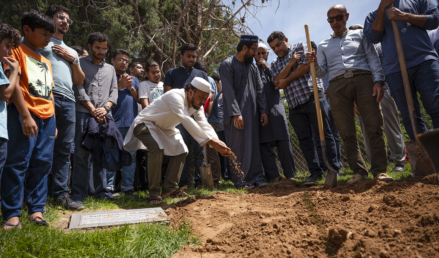 People sprinkle dirt over the grave of Muhammad Afzaal Hussain, 27, at Fairview Memorial Park in Albuquerque, N.M., on August 5, 2022. (The Albuquerque Journal via AP)