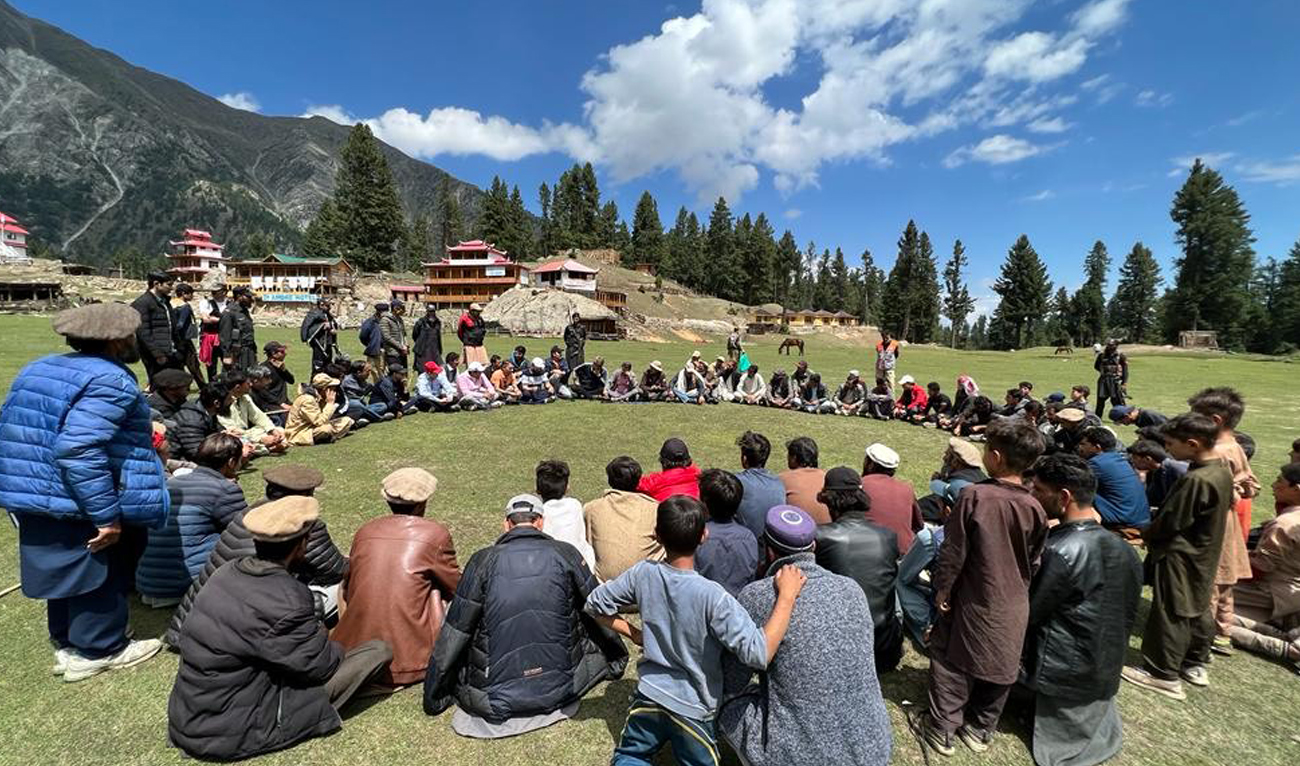 Government officials and community members sit in a circle during a jirga held at Fairy Meadows in Diamer district of Gilgit-Baltistan, Pakistan, on August 6, 2022. (Office of Diamer Deputy Commissioner)