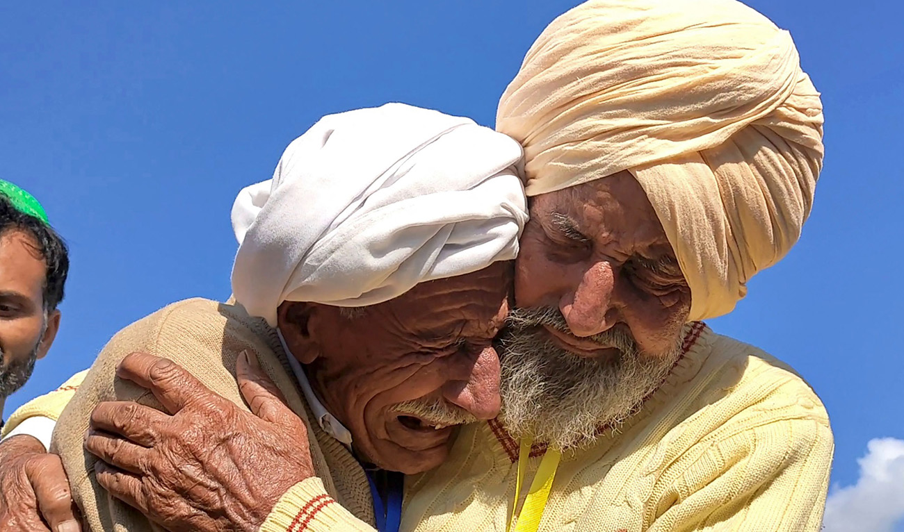 Indian Sikh labourer Sika Khan (R) embraced his elder brother Sadiq Khan from Pakistan near the India-Pakistan border at the Kartarpur corridor on January 12, 2022. (Nasir Dhillon/AFP)