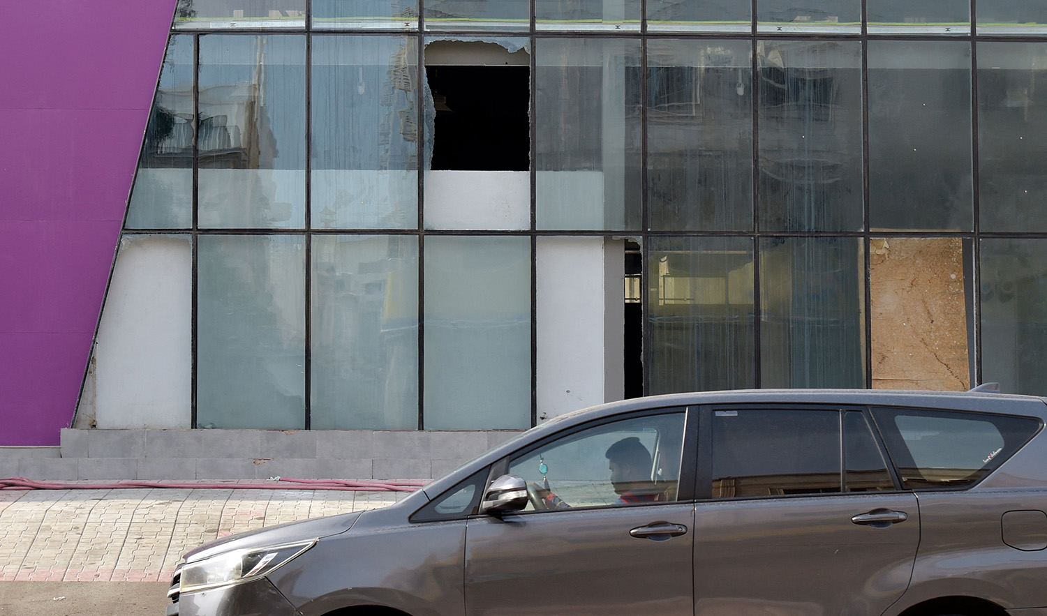 A picture taken on August 12, 2022 shows shattered glass as a man walks in front of the building where according to Saudi officials a wanted militant blew himself up while being arrested by security forces in Jeddah this week. (AFP)
