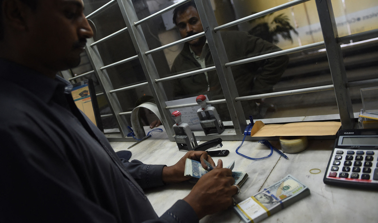A Pakistani currency dealer counts rupees and US dollars at a currency exchange in Karachi on December 17, 2015. (AFP/File)