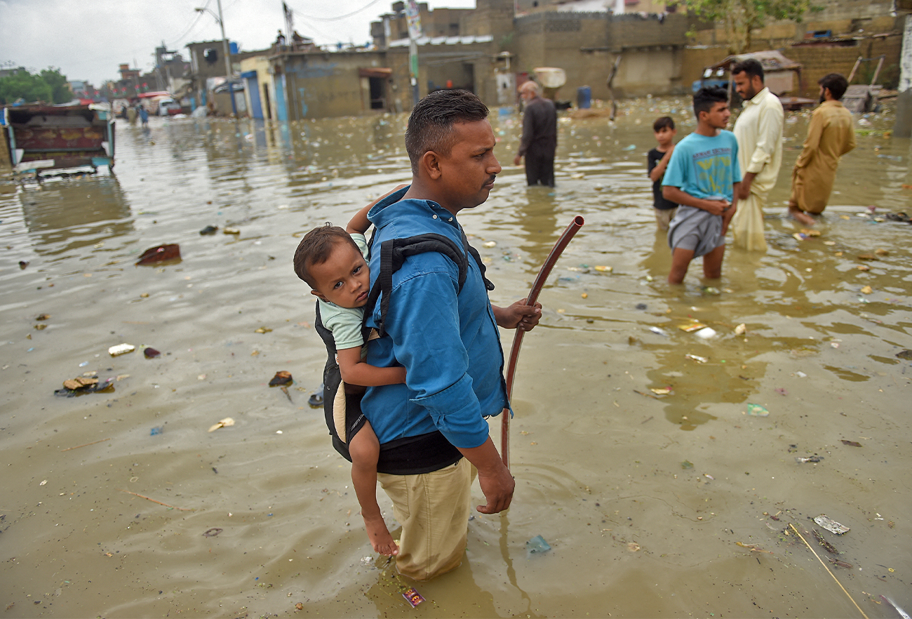 People wade across a flooded street after heavy monsoon rainfall in Karachi, Pakistan, on July 25, 2022. (AFP)