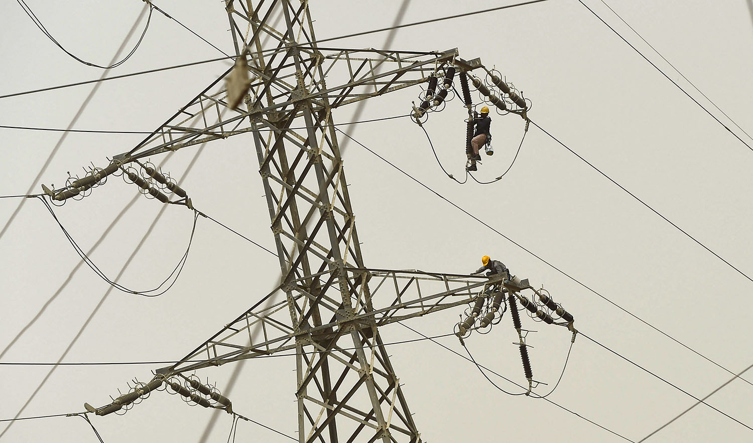 Technicians of the Karachi Electric Corporation work on a high voltage line in Karachi, Pakistan, on May 30, 2018. (AFP/File)