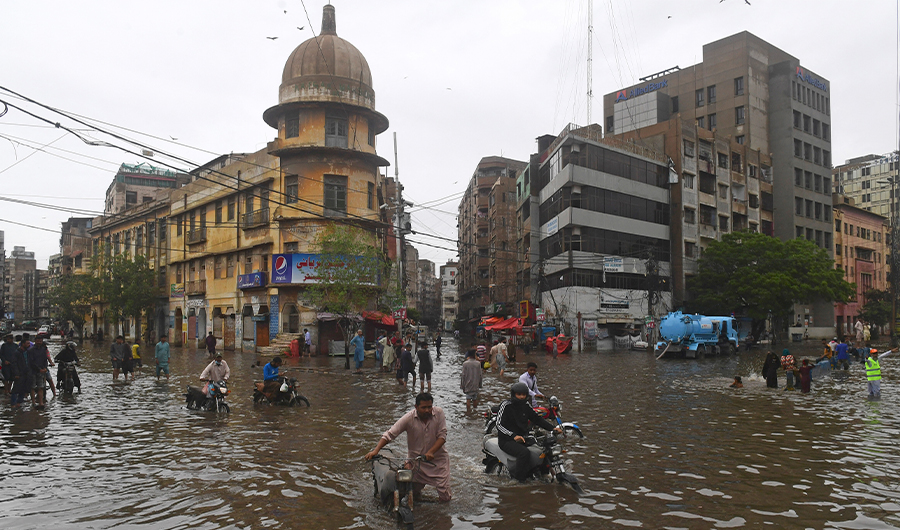 People wade across a flooded street after heavy monsoon rainfall in Karachi on July 25, 2022. (AFP/FILE)