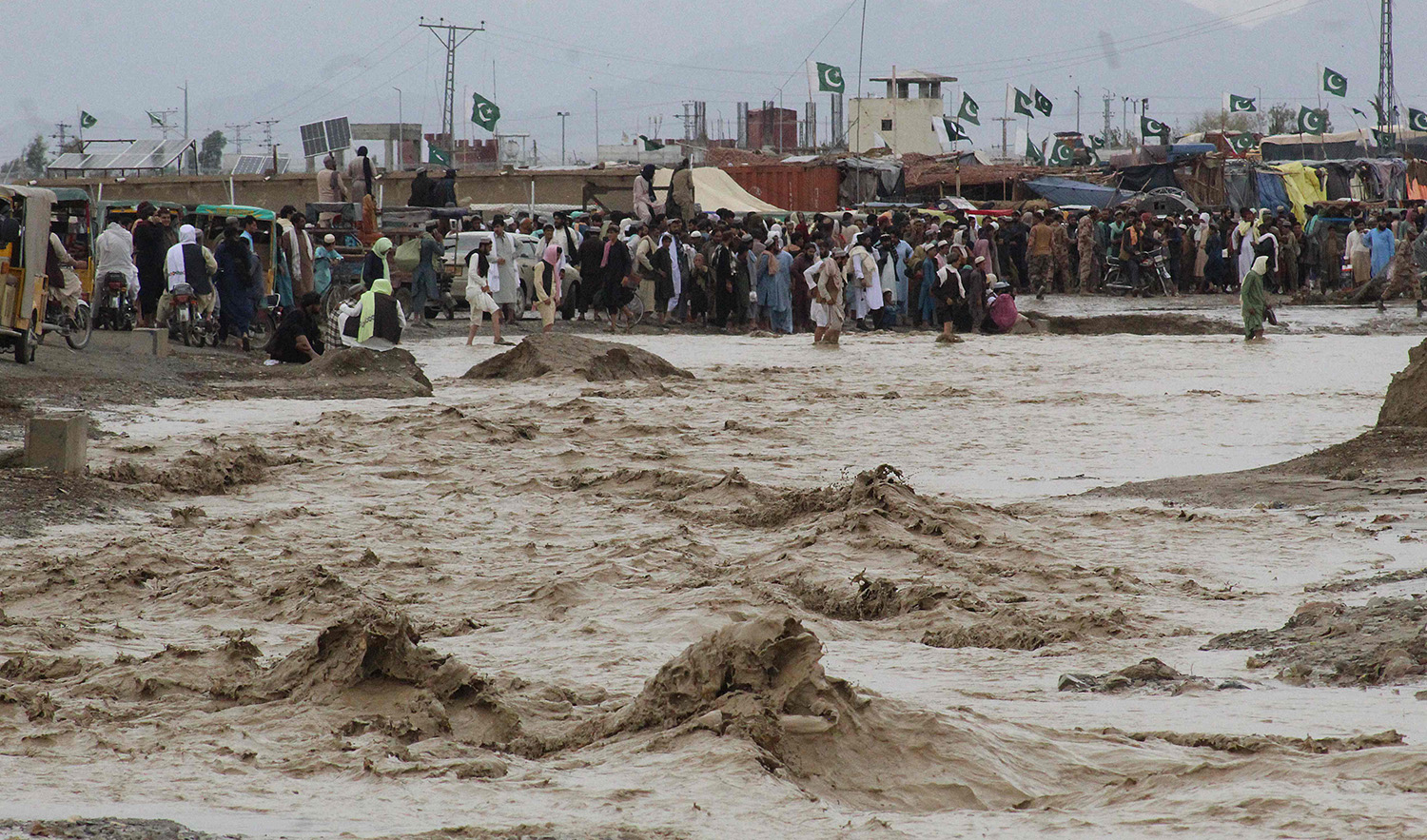 People wade through flooded mud water after heavy monsoon rainfall in the border town of Chaman in Pakistan's Balochistan province on August 25, 2022. (AFP)