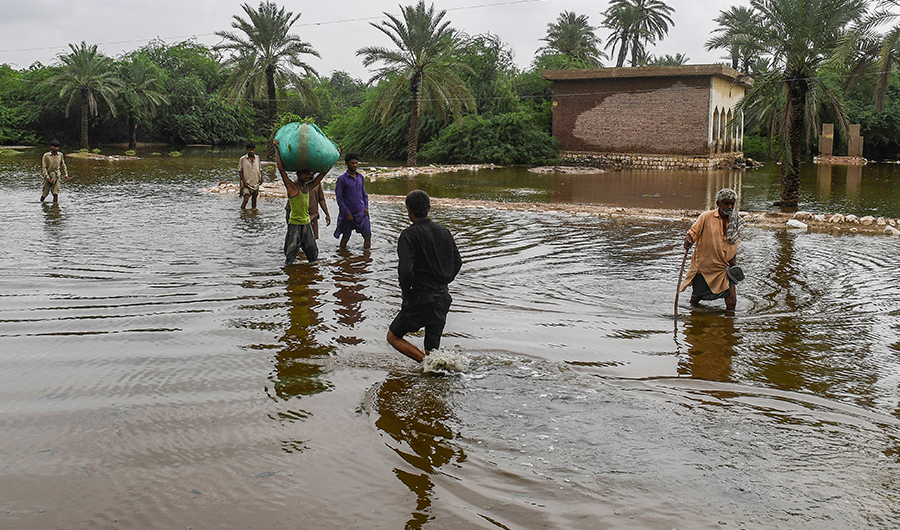 Residents wade through a flooded street after heavy monsoon rainfalls in Sukkur of Sindh province, southern Pakistan on August 26, 2022. (AFP)