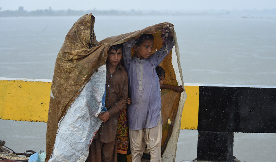 Children displaced with their families by flooding due to heavy monsoon rains use a plastic sheet to shelter along a road on the outskirts of Sukkur, Sindh province, on August 27, 2022. (AFP)