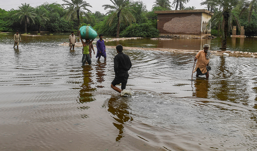 Residents wade through a flooded street after heavy monsoon rainfalls in Sukkur of Sindh province, southern Pakistan on August 26, 2022. (AFP)
