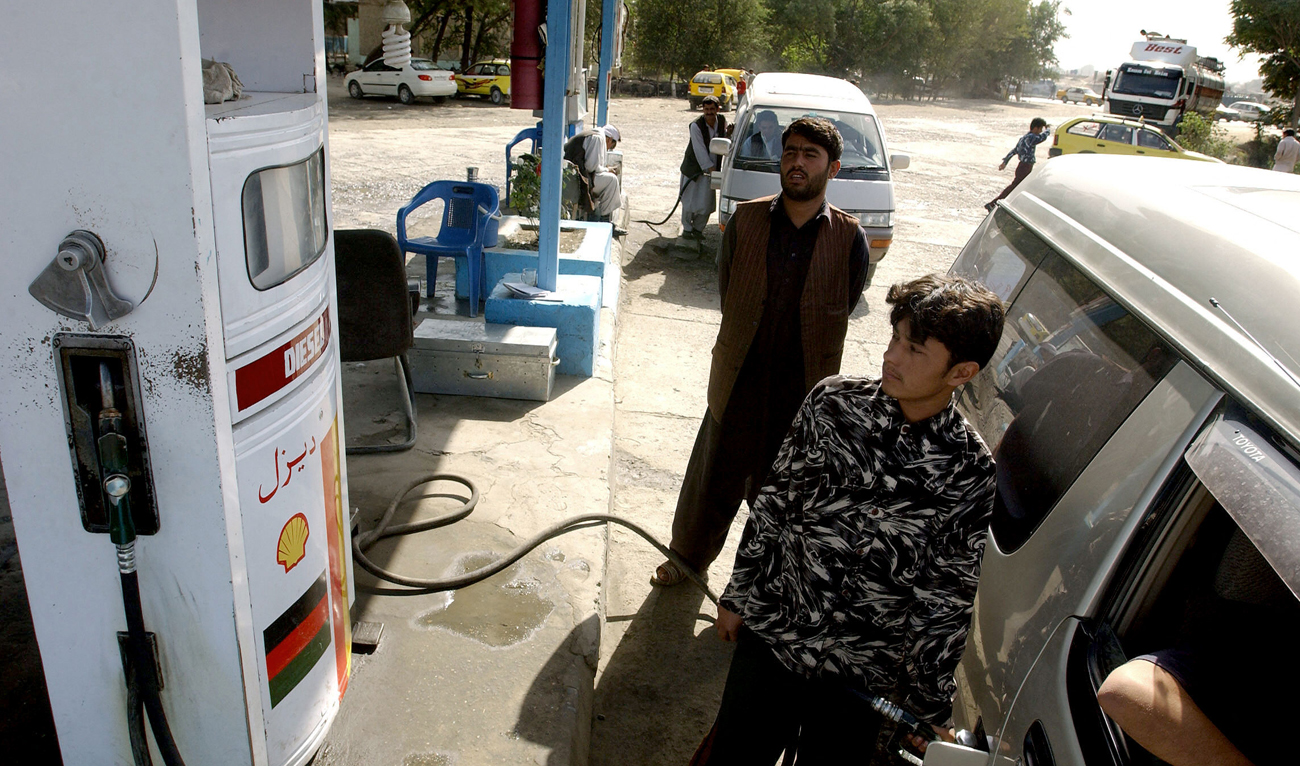 Afghan fuel station employees watch pump indicators as they fill up cars with fuel at a service station in Kabul, Afghanistan on 30 August 2005. (AFP/File)