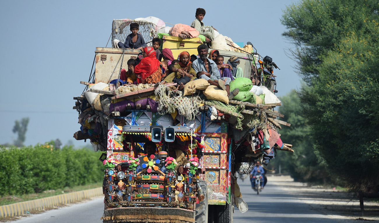 Displaced people sit on a tractor with their belongings as they make their way to reach safer place camp after fleeing from their flood hit homes following heavy monsoon rains in Shikarpur of Sindh province on August 30, 2022. (AFP)