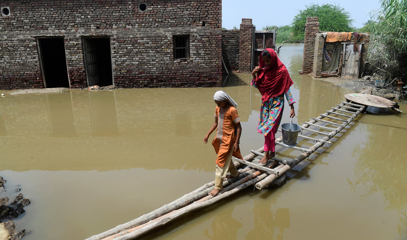 Flood affected people walk on a temporary bamboo path near their flooded house in Shikarpur of Sindh province on August 29, 2022. (AFP)