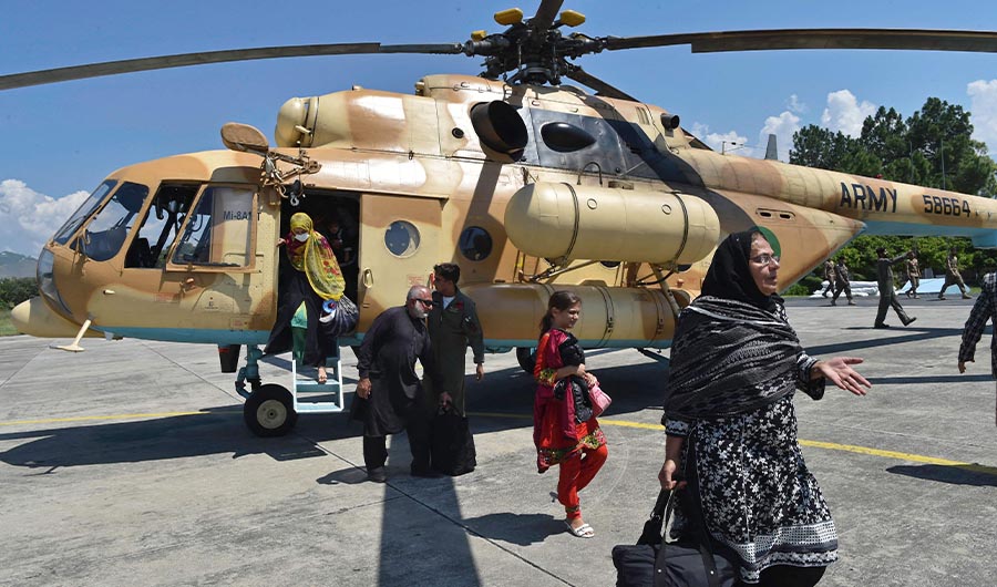 Stranded local tourists disembark from a Pakistan army helicopter after they were rescued by army from the flood-hit tourist areas in Saidu Sharif, the capital of Swat valley in the Khyber Pakhtunkhwa province on August 30, 2022. (AFP)