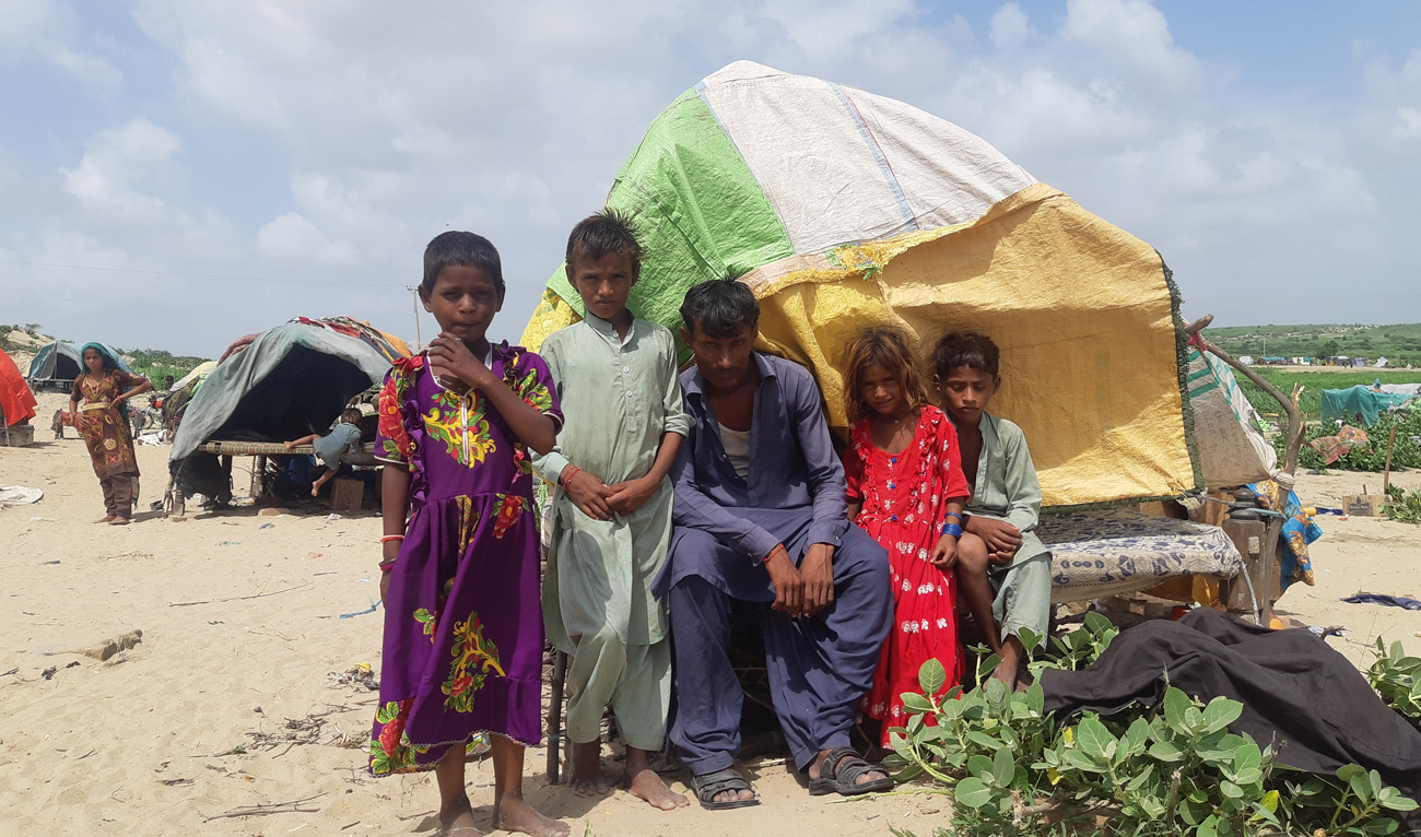 A man poses with children at a climate migrants’ relief camp in Umerkot, Pakistan on August 28, 2022. (AN Photo/ Zulfiqar Kunbhar)