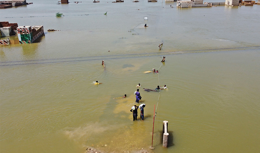 This aerial photograph taken on August 31, 2022 shows flood-affected people wading through a flooded area after heavy monsoon rains in Jaffarabad district of Balochistan province. (AP)