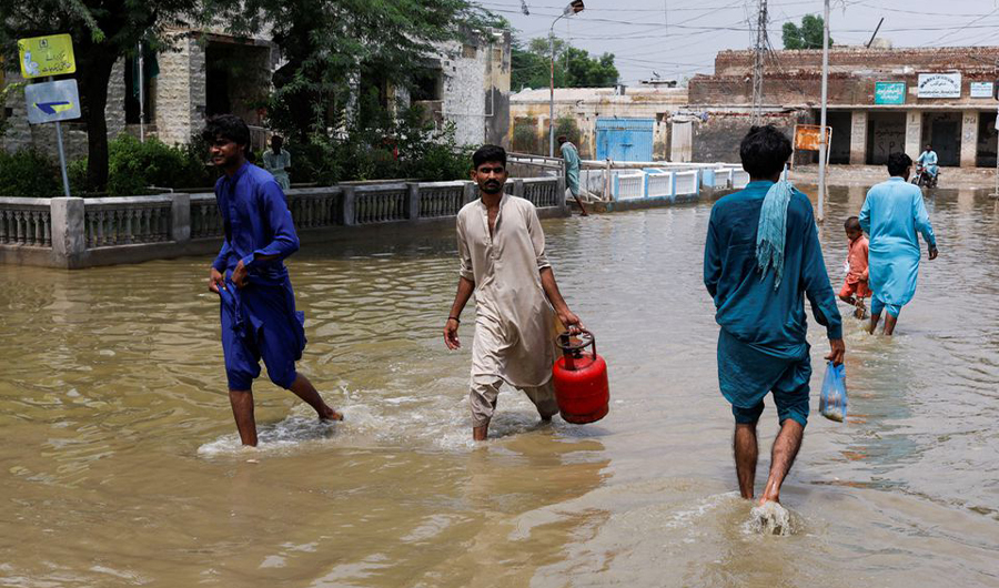 Men walk through rain waters, following rains and floods during the monsoon season in Jacobabad, Pakistan August 30, 2022. (REUTERS)