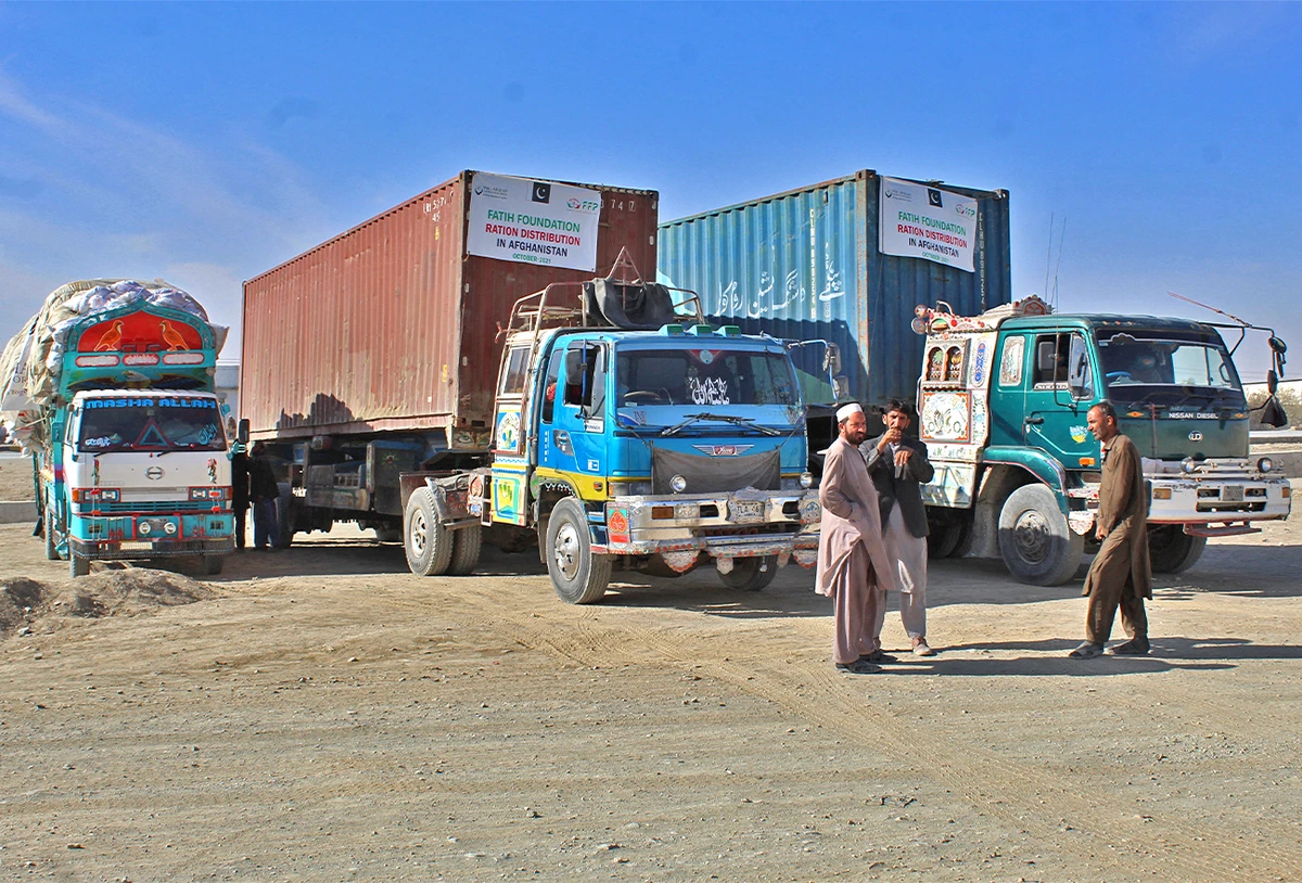 Drivers stand in front of their trucks loaded with relief materials for the distressed Afghan people before crossing through the Chaman border on December 17, 2021. (AFP/File)