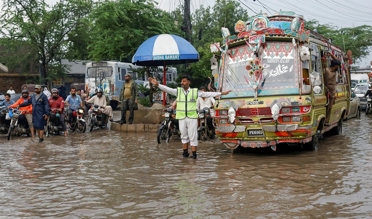 A police officer controls traffic while standing amid rain waters during the monsoon season in Karachi, Pakistan on August 10, 2022. (REUTERS)