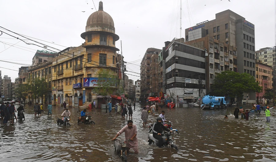 People wade across a flooded street after heavy monsoon rainfall in Karachi on July 25, 2022. (AFP/FILE)