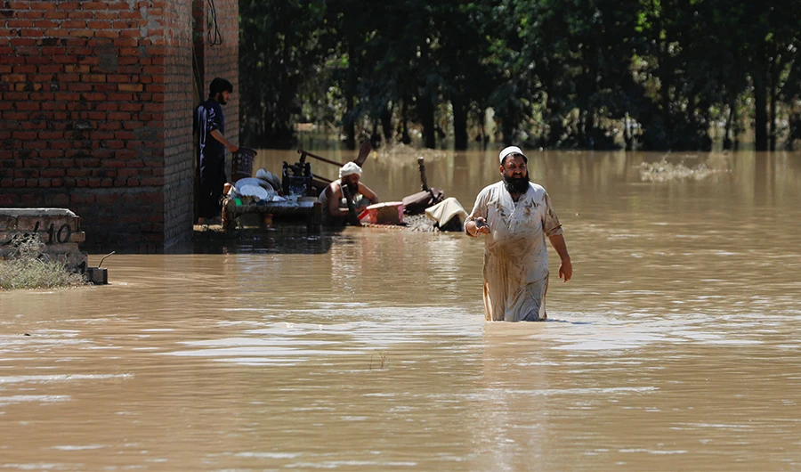 A man wades through flood waters trying to salvage his belongings following rains and floods during the monsoon season in Charsadda, Pakistan August 28, 2022. (REUTERS)