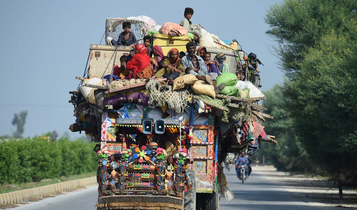 Displaced people sit on a tractor with their belongings as they make their way to reach safer place camp after fleeing from their flood hit homes following heavy monsoon rains in Shikarpur of Sindh province on August 30, 2022. (AFP)