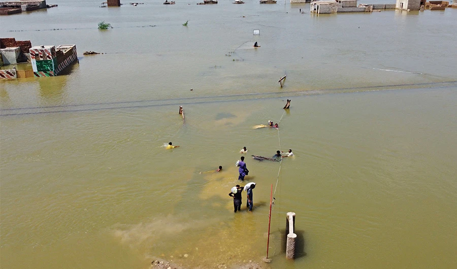 This aerial photograph taken on August 31, 2022 shows flood-affected people wading through a flooded area after heavy monsoon rains in Jaffarabad district of Balochistan province. (AP)