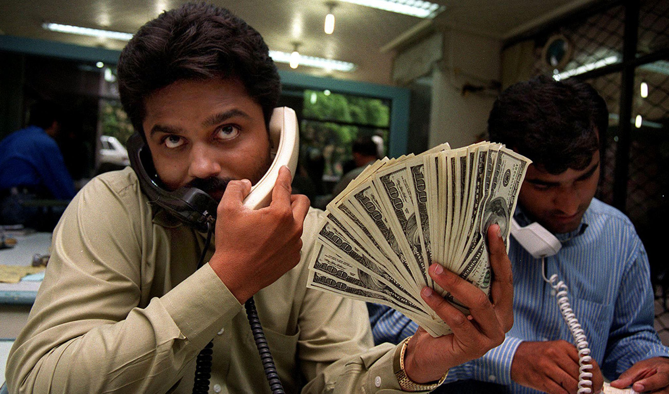 Pakistani money dealers busy on telephones amid a spurt in demand for the green back in the port city of Karachi, 27 May 2000. (AFP/File)