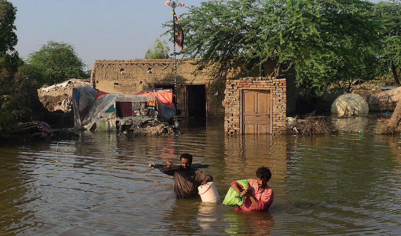 Flood affected people carry belongings out from their flooded home in Shikarpur, Sindh province, on August 31, 2022. (AFP)